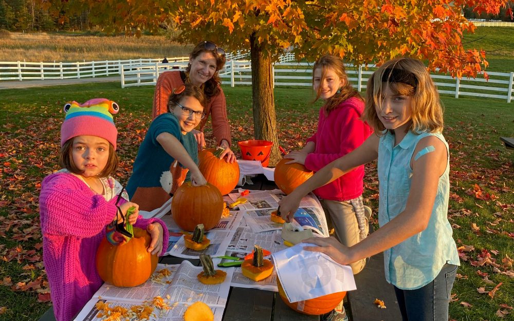 people carving pumpkins in fall foliage at pineland farms