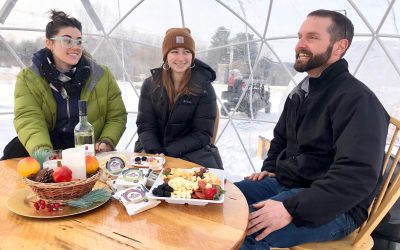 Friends smiling and enjoying each others company inside a heated snow globe.