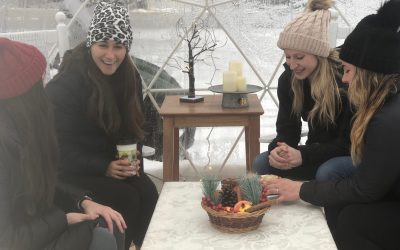 Four friends enjoying a heated snow globe experience at Pineland Farms.